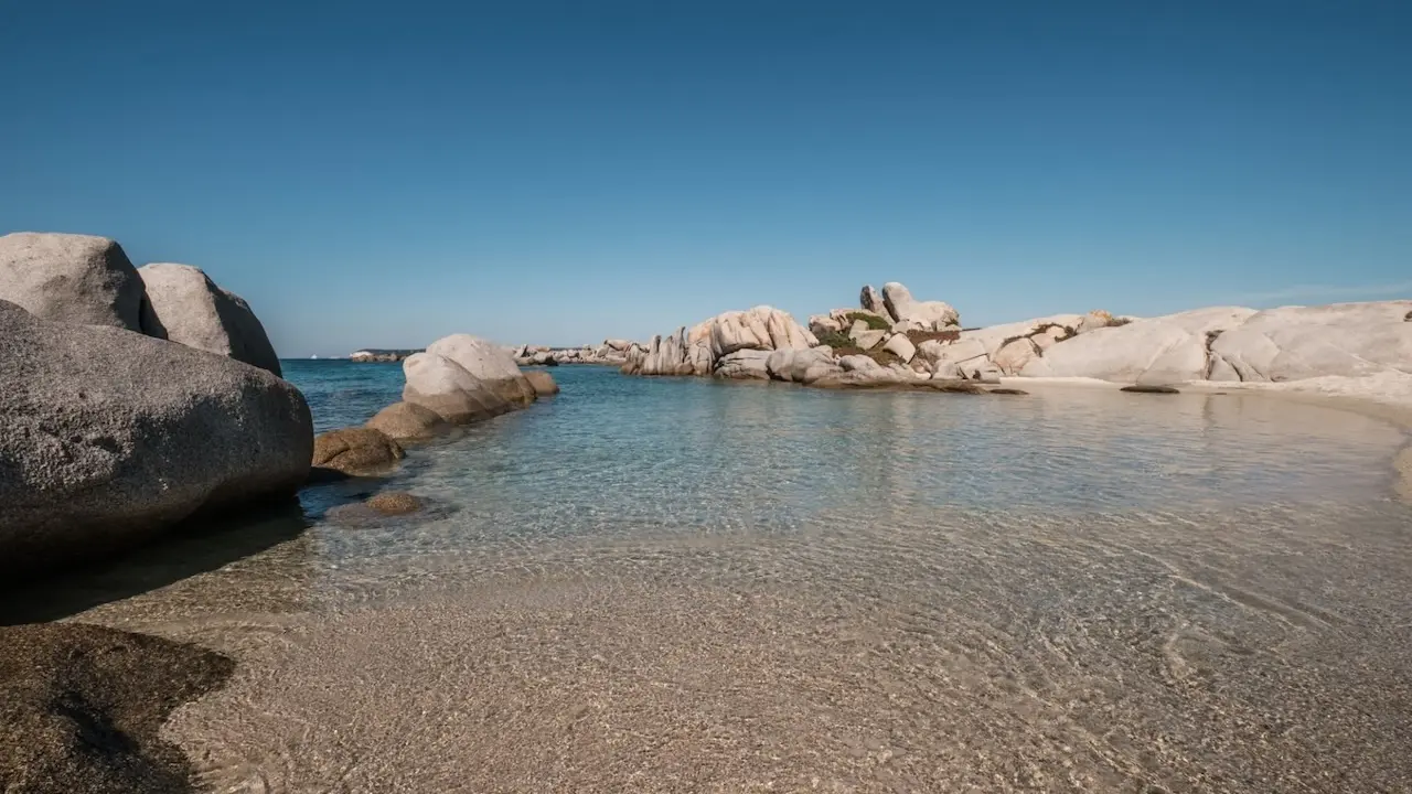 plage de l'île Cavallo bordé de grands rochers érodés lors d'une location privée de bateau